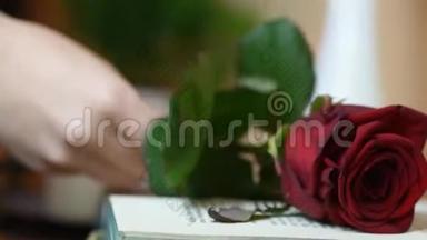 在桌子上拿起一朵红玫瑰，上面放着书和蜡烛